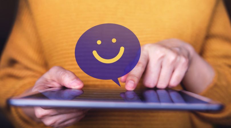 how to get clients featured image woman holding a tablet with a happy face graphic to illustrate happy clients
